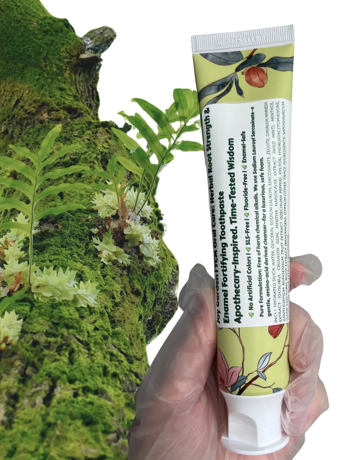 Joy Garden Herbal Root Strength and Enamel Fortifying Toothpaste tube held against mossy tree trunk with wild ferns